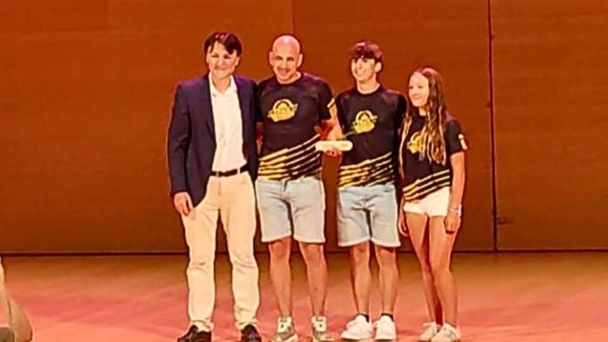 El president Èric Torres, segon per l'esquerra, rep el premi acompanyat de dos esportistes del club.