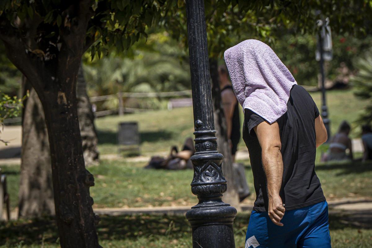 Una persona trata de cubrirse del sol en el parque de la Ciutadella, en Barcelona.