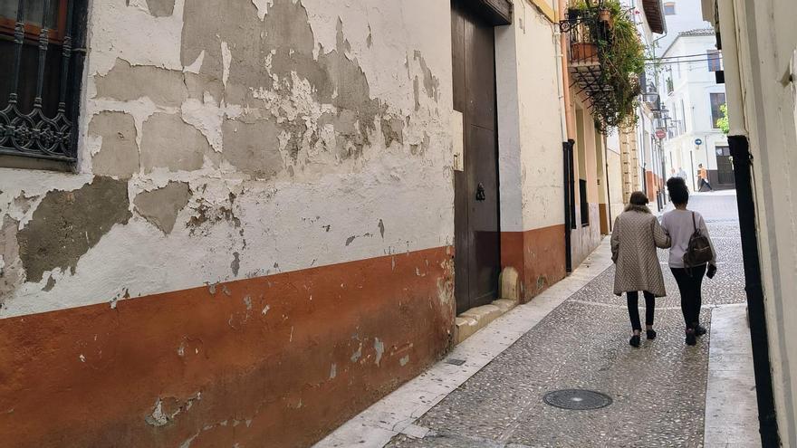 Una pareja pasa ante una de las dos fachadas de la propiedad que se vende en Xàtiva.