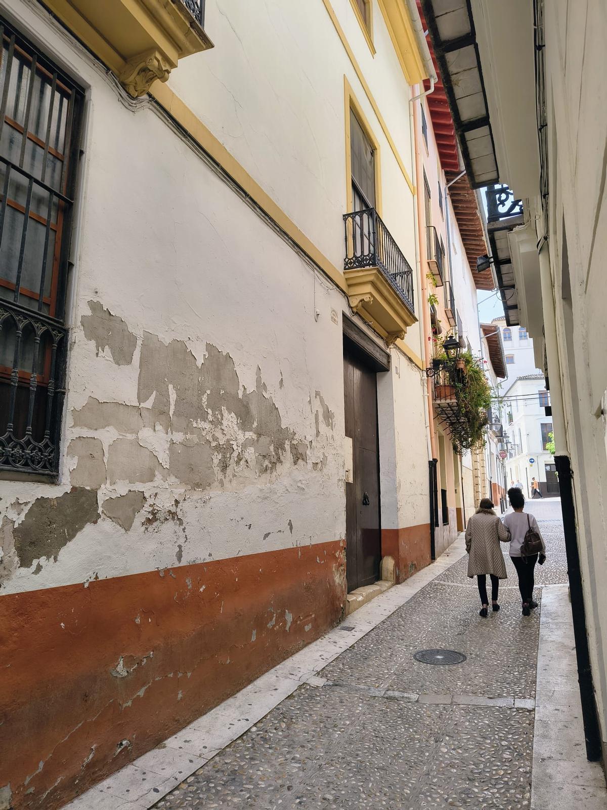 Una pareja pasa ante una de las dos fachadas de la propiedad que se vende en Xàtiva.