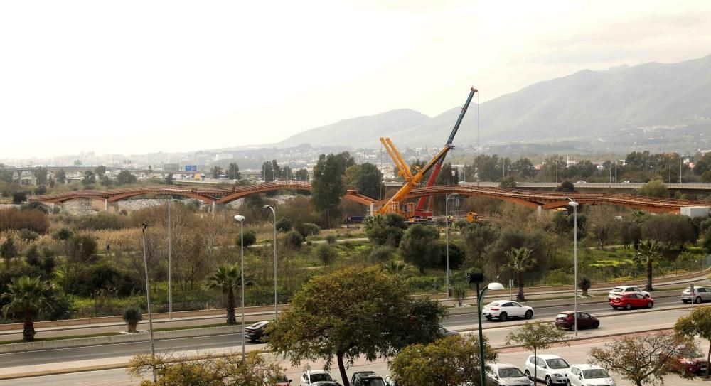 La instalación del último tramo del puente de madera sobre el río Guadalhorce ha comenzado este martes.