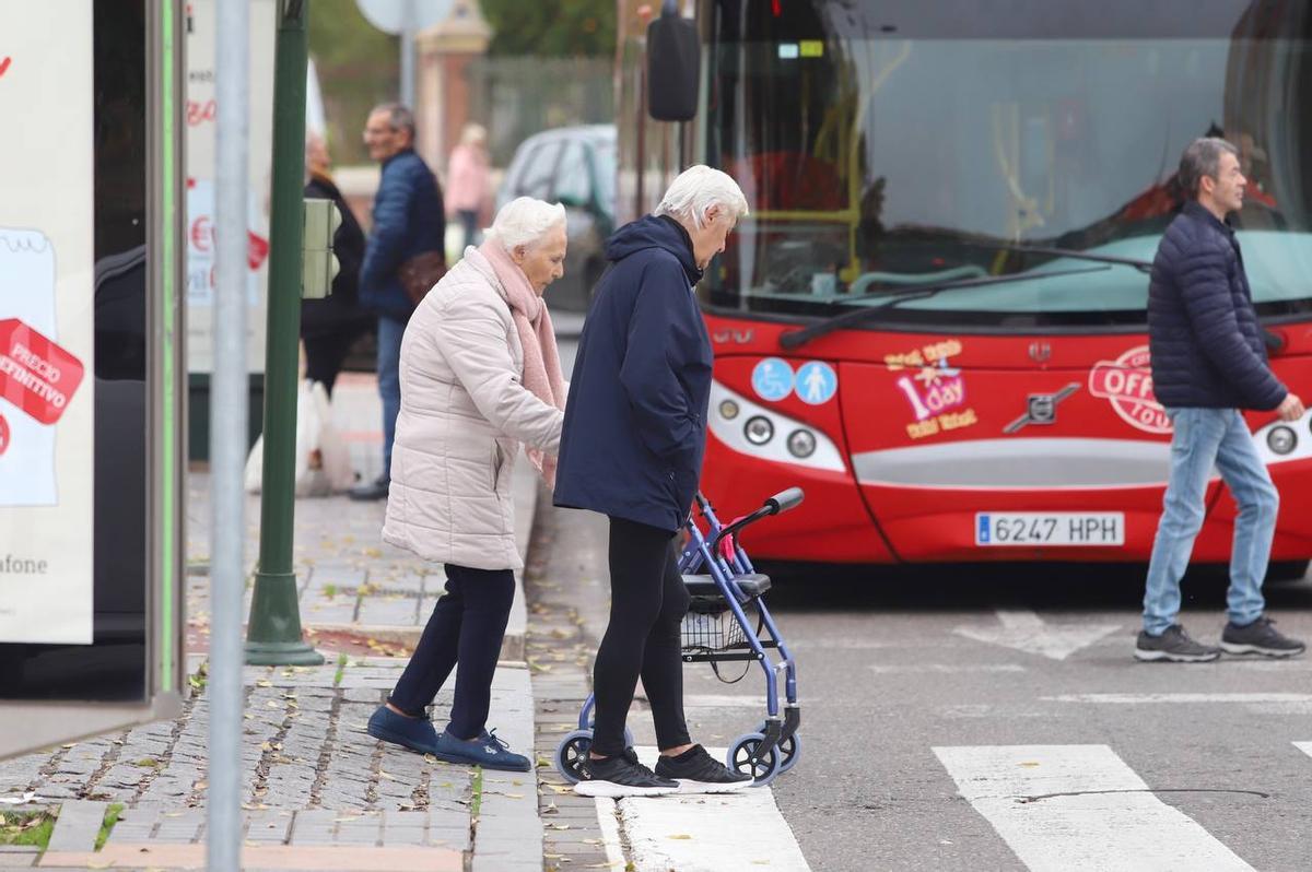 Dos personas mayores cruzan un paso de peatones.