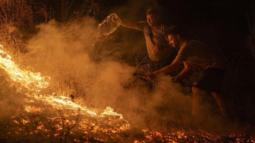 Dos homes miren d’apagar el foc d’un dels incendis que es van desencadenar a Ourense aquest estiu.  | BRAIS LORENZO