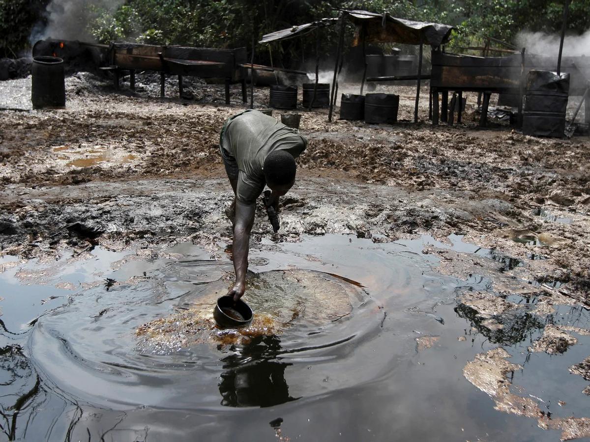 Un hombre recoge agua contaminada en una refinería de petróleo ilegal cerca del río Nun, en el delta del Níger, en Nigeria.