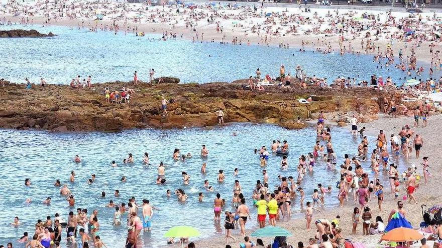 La playa de Riazor, este verano, llena de gente por las altas temperaturas.