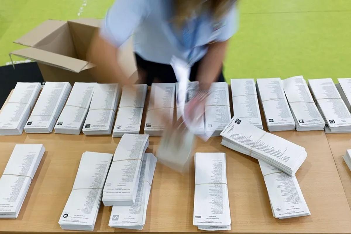 Paleletas de distintos partidos junto a una mesa electoral.