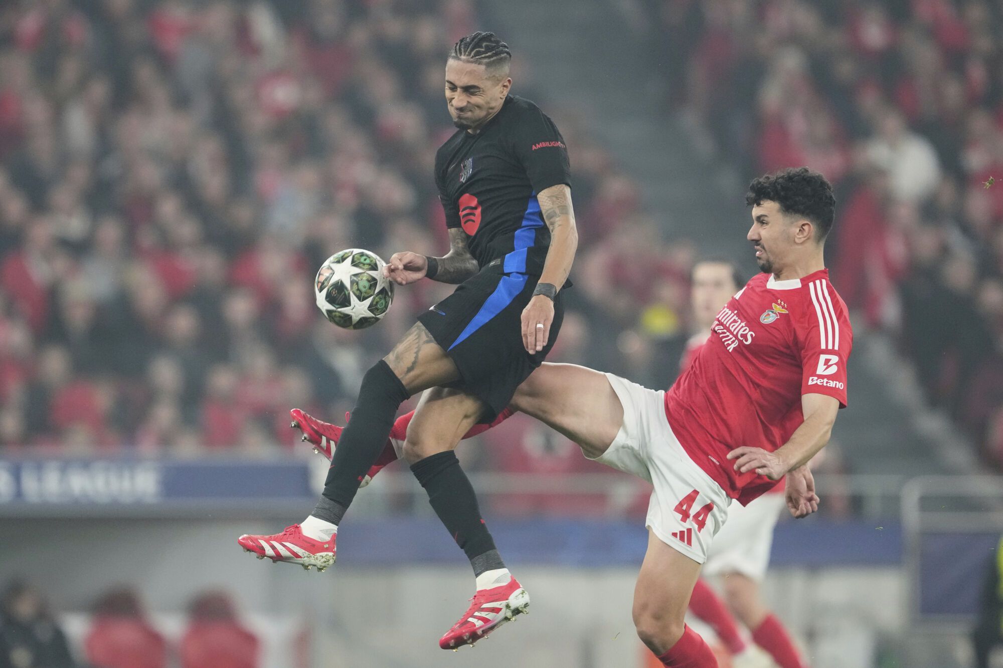 Barcelona's Raphinha, left, is challenged by Benfica's Tomas Araujo during the Champions League round of 16 first leg soccer match between SL Benfica and FC Barcelona at the Luz stadium in Lisbon, Wednesday, March 5, 2025. (AP Photo/Armando Franca)