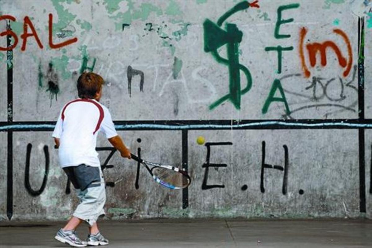 Un nen juga en un frontó d’Arrasate (Guipúscoa) ple de pintades al·lusives a ETA, ahir.