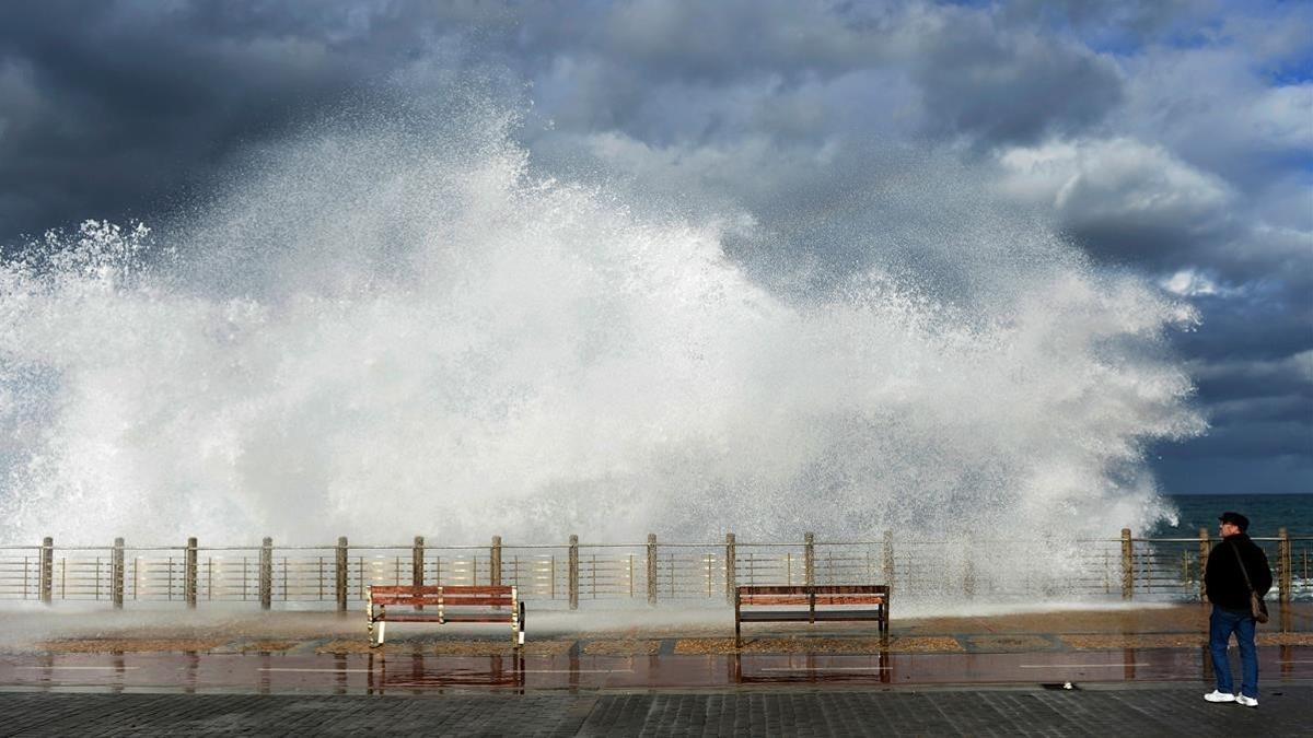 Un hombre observa olas gigantes en un paseo marítimo de San Sebastián. Se han emitido alertas en varias regiones de España por fuertes vientos.