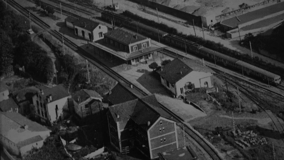 Antigua fotografía que toma una vista aérea del nudo ferroviario de Villabona, donde se aprecia las vías a ambos lados de las instalaciones de la estación, que ya tiene instala la marquesina de forjado que rodea todo el perímetro del edificio.