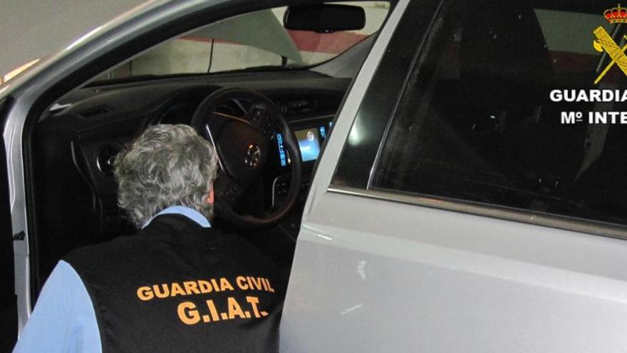 Un agente de la Guardia Civil, con uno de los coches utilizados en la estafa