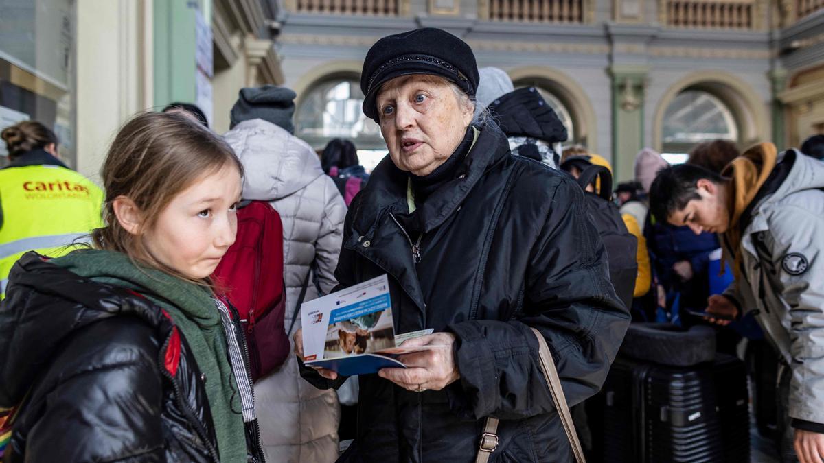 Una mujer de avanzada edad junto a su nieta procedentes de Ucrania compran billetes de tren en la estación de Przemysl, Polonia