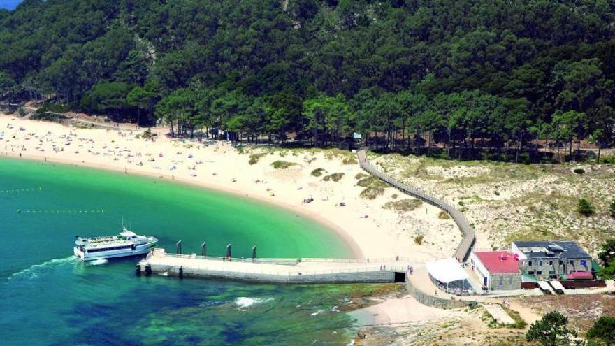 Un barco de pasajeros se aproxima al embarcadero de Cíes con la playa de Rodas al fondo. // Ricardo Grobas