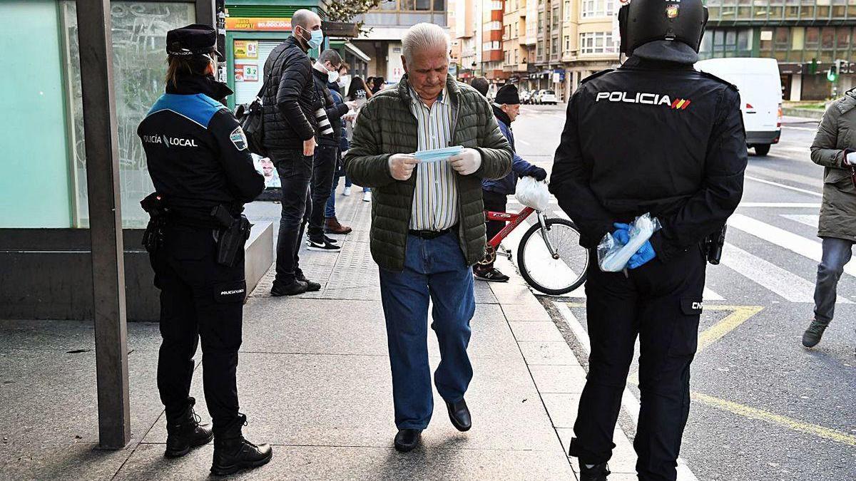 Policías locales y nacionales reparten mascarillas en la plaza de Pontevedra, en A Coruña.