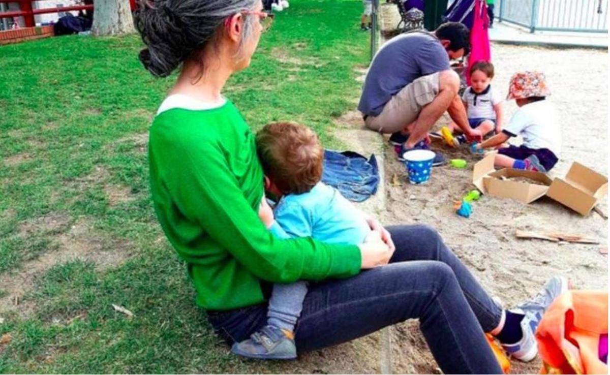 Un madre amanta a su bebé, en un parque.