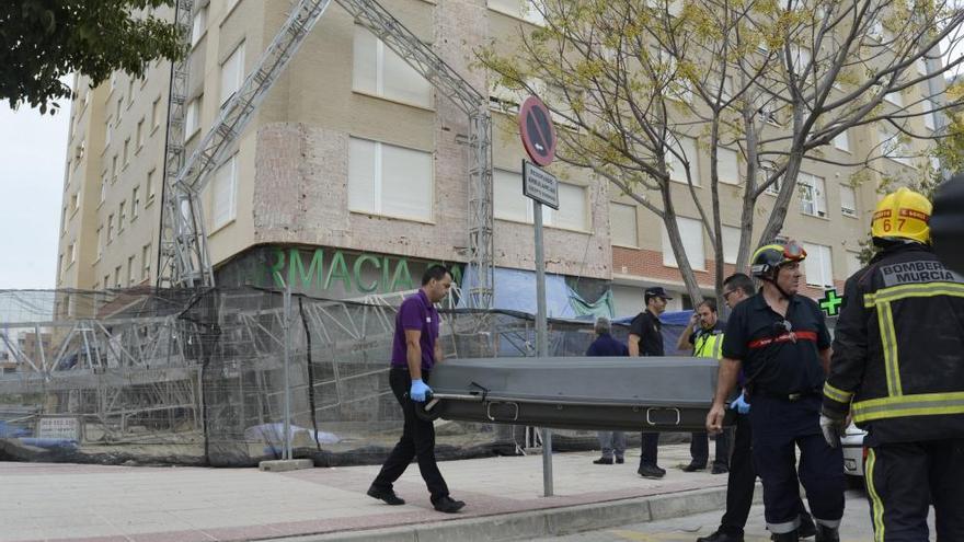 Levantamiento del cadáver de uno de los obreros; al fondo, el andamio, doblado, desde el que se precipitaron.