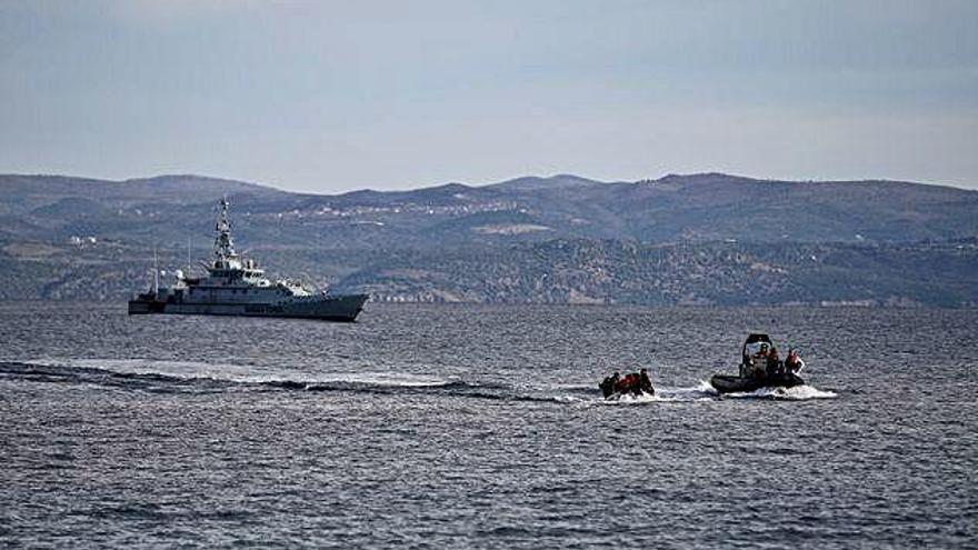 Una llanxa de rescat acompanya una barca de migrants, mentre al fons patrulla un vaixell de Frontex