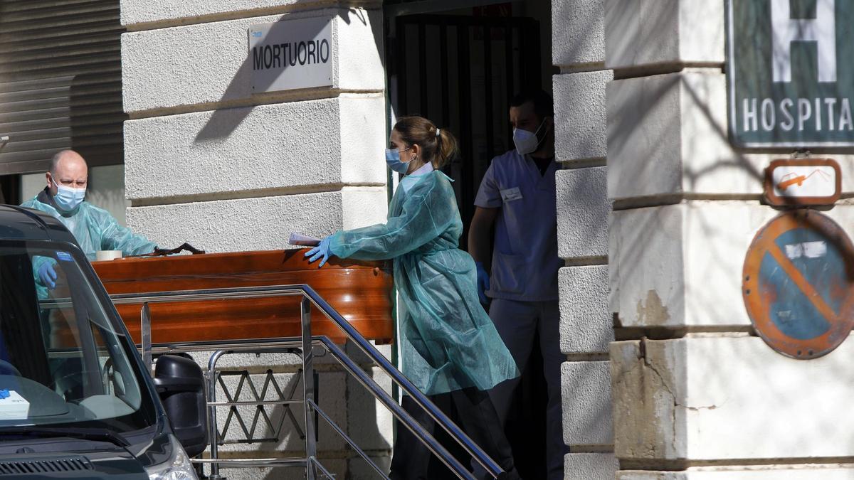 Operarios funerarios trabajando con EPIs en el mortuorio del Hospital General de València.