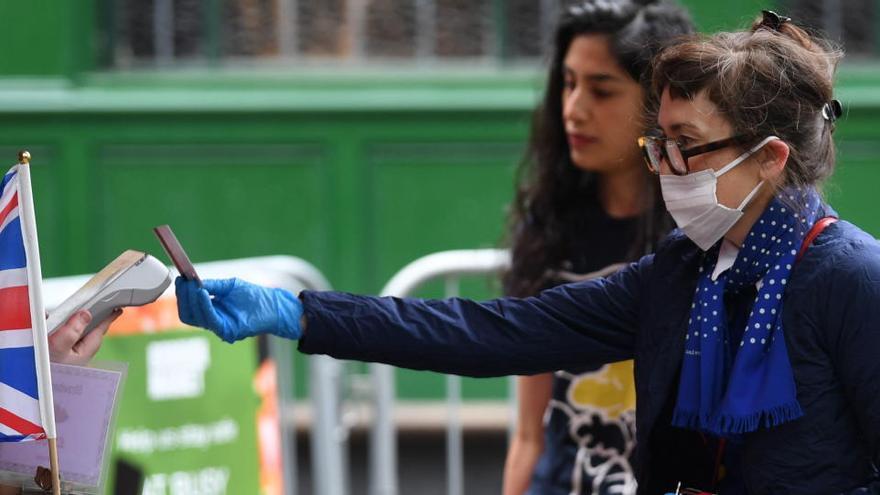 Una clienta con una mascarilla compra productos en el Borough Market de Londres.