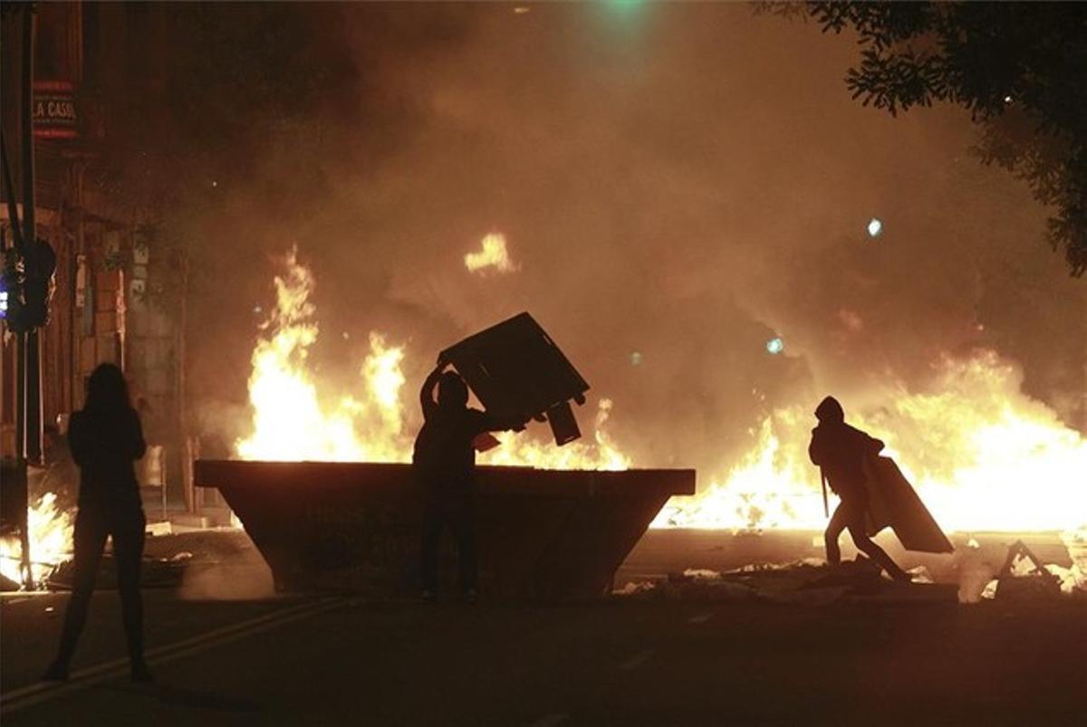 Dues persones llancen objectes a les flames per alimentar una gran foguera.