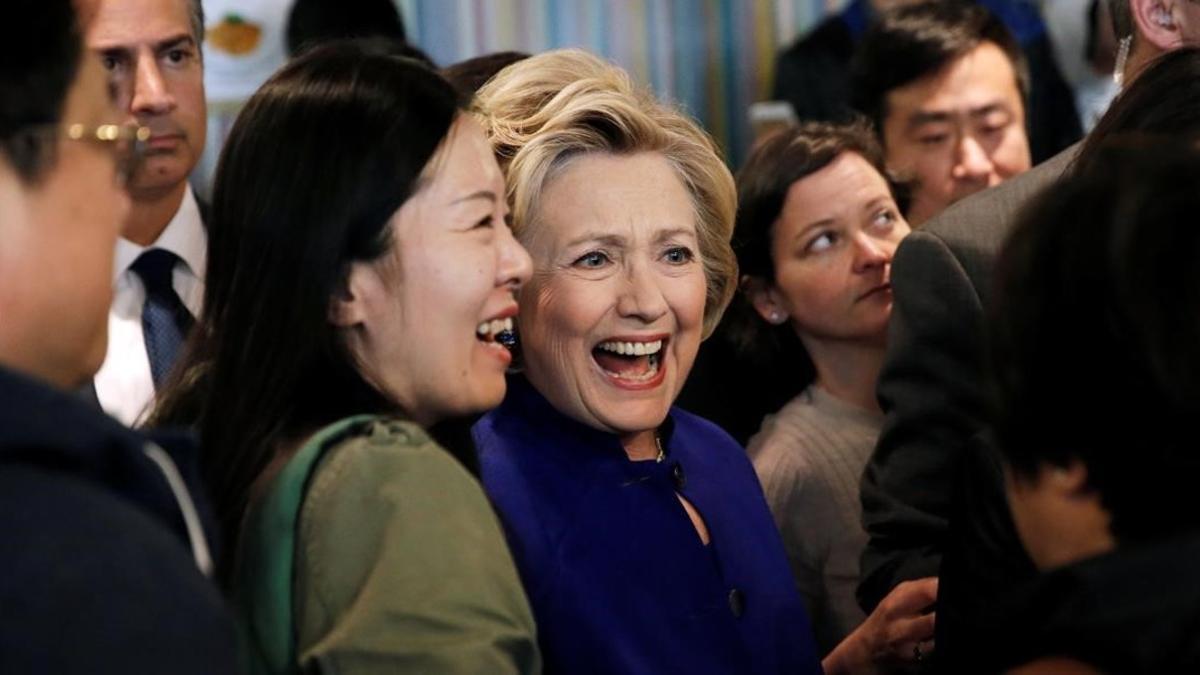 Clinton (centro) saluda a la audiencia durante una visita al restaurante Kung Fu Tea, en Queens (Nueva York), este lunes.