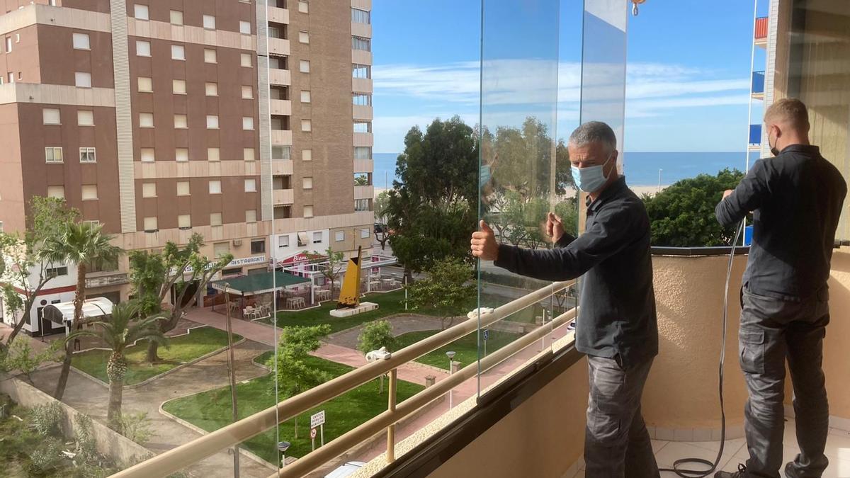 Unos operarios instalan unas ‘cortinas de cristal’ en una terraza con vistas a la playa de la Concha, en Orpesa.