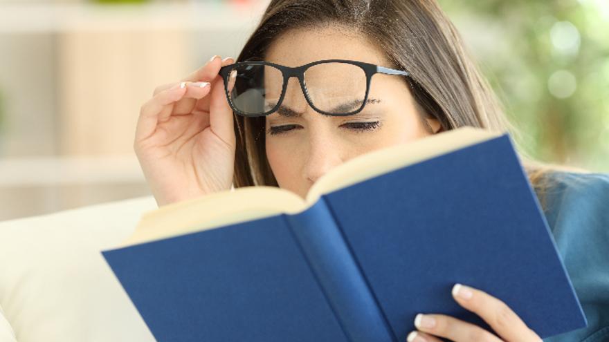 Una mujer fuerza la vista para poder leer un libro.