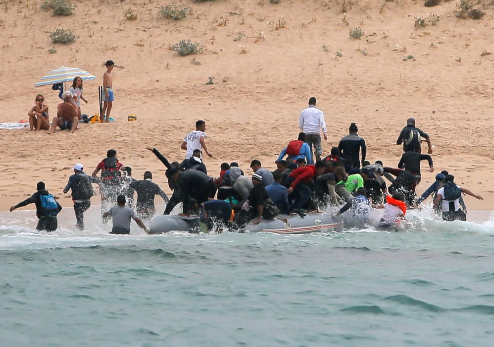 Una patera llega a una playa de Cádiz ante la mirada de los bañistas