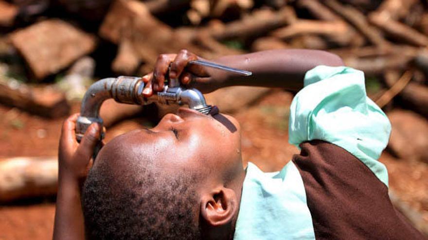 Un niño bebe agua de un grifo instalado en el campo de desplazados de Nairobi, Kenia