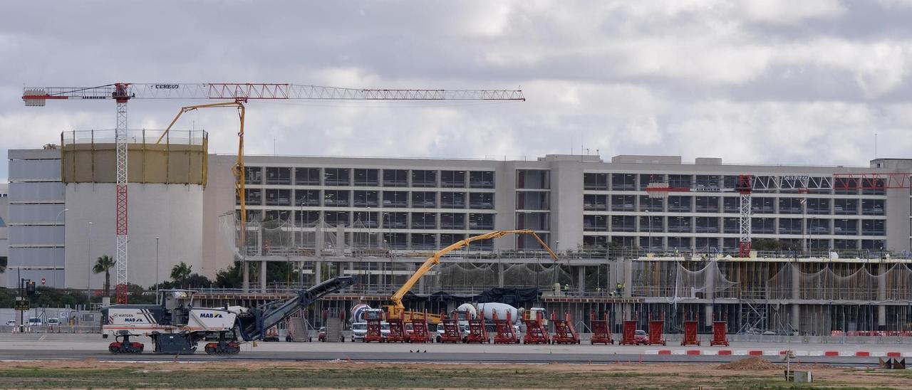 Maquinaria de pavimentación sobre la pista de rodadura del aeropuerto de Palma, con la terminal también en obras al fondo