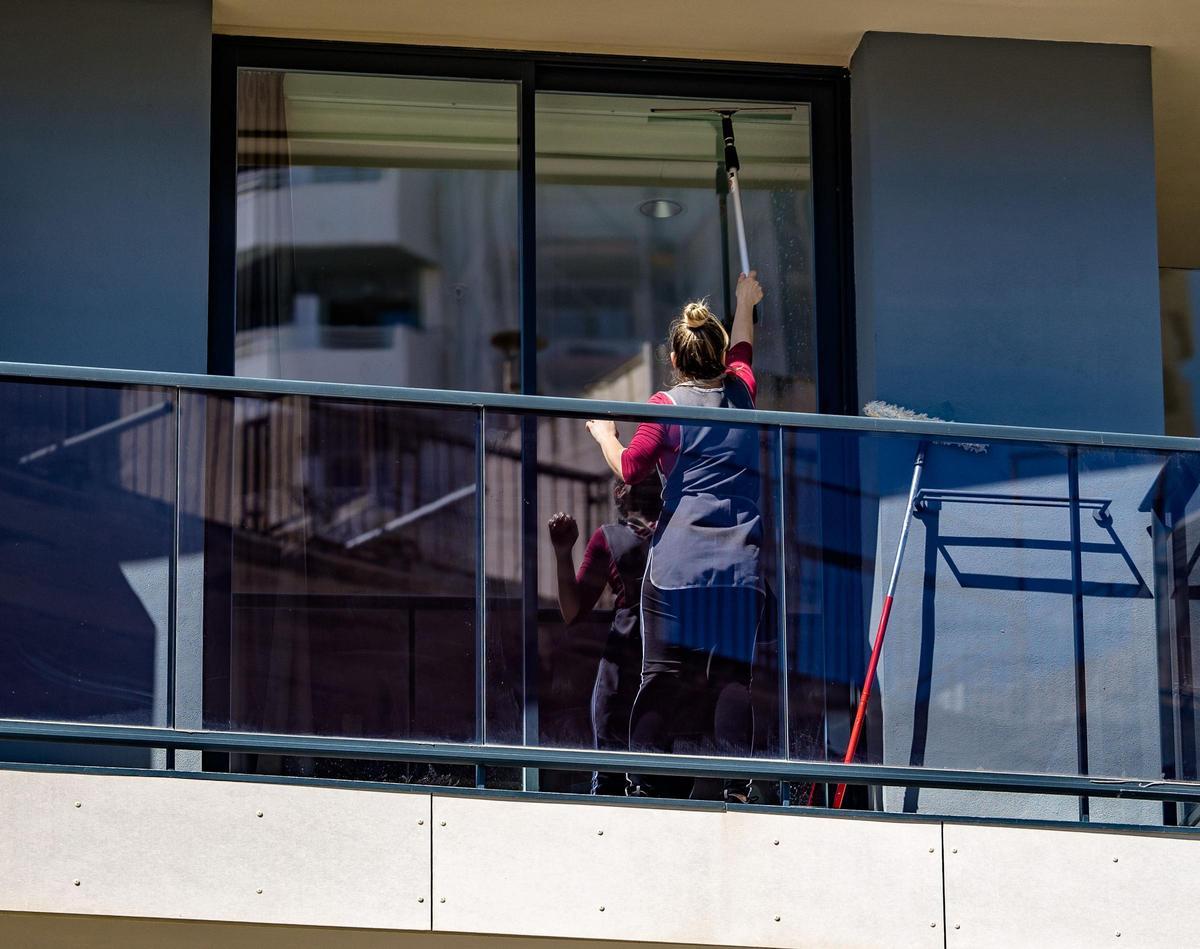 Una empleada de hogar limpia las ventanas de una vivienda. Este colectivo se beneficiará del alza del SMI.