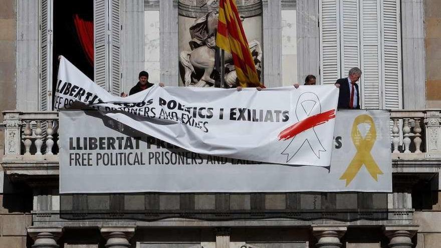 Personal de la Generalitat cubre, en la mañana de ayer, la pancarta con el lazo amarillo de la fachada del Palau con un cartel idéntico, pero con un lazo blanco tachado en rojo. // Efe