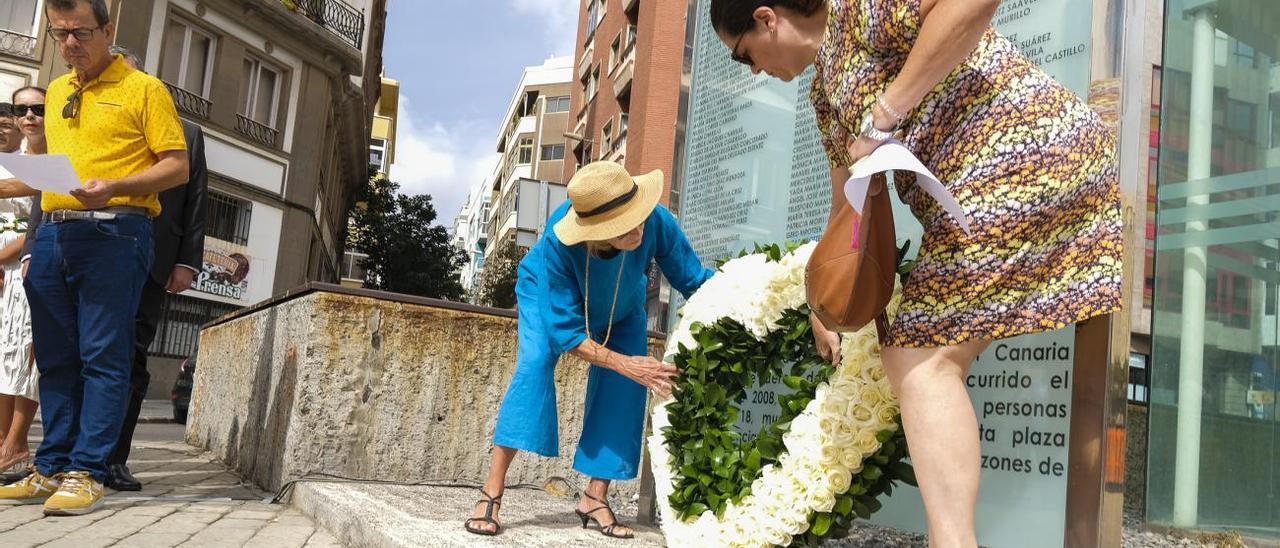 Estrella Nespereira, de azul y con pamela, coloca junto a otra persona la corona de flores en honor a las víctimas del JK5022