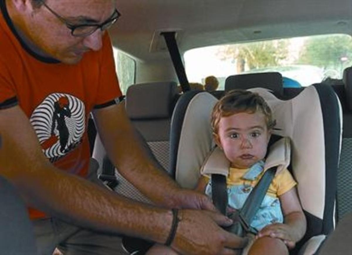 Un conductor sujeta a su hijo a la sillita del coche.