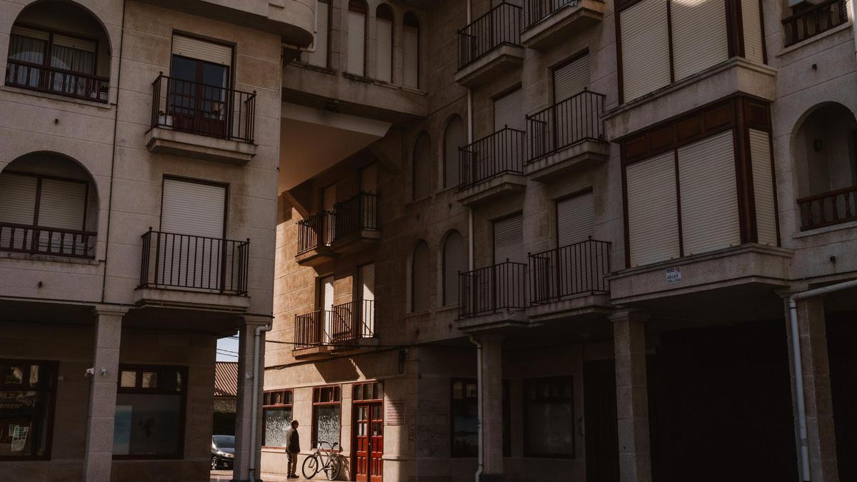 Un vecino observa un escaparate en el centro de Noja, rodeado de casas con las persianas bajadas.