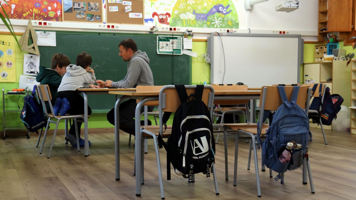 Dos alumnes escolten les explicacions del docent, en una imatge de recurs.