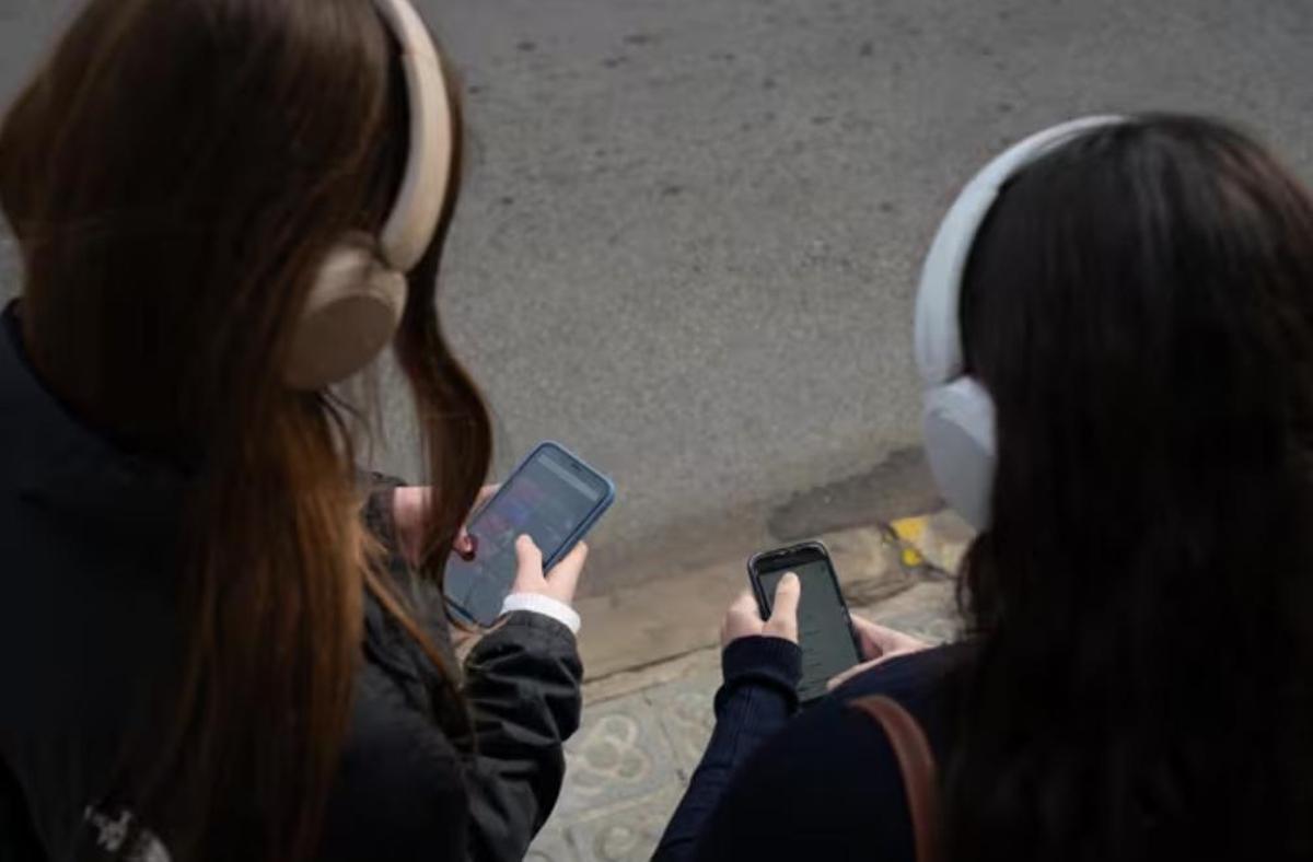 Dos jóvenes usan el teléfono móvil.