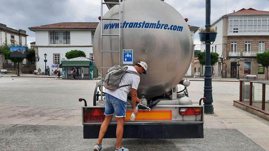 Un hombre llena botellas de agua de la cisterna de la plaza García Irmáns. |   // DANIEL ABELENDA.