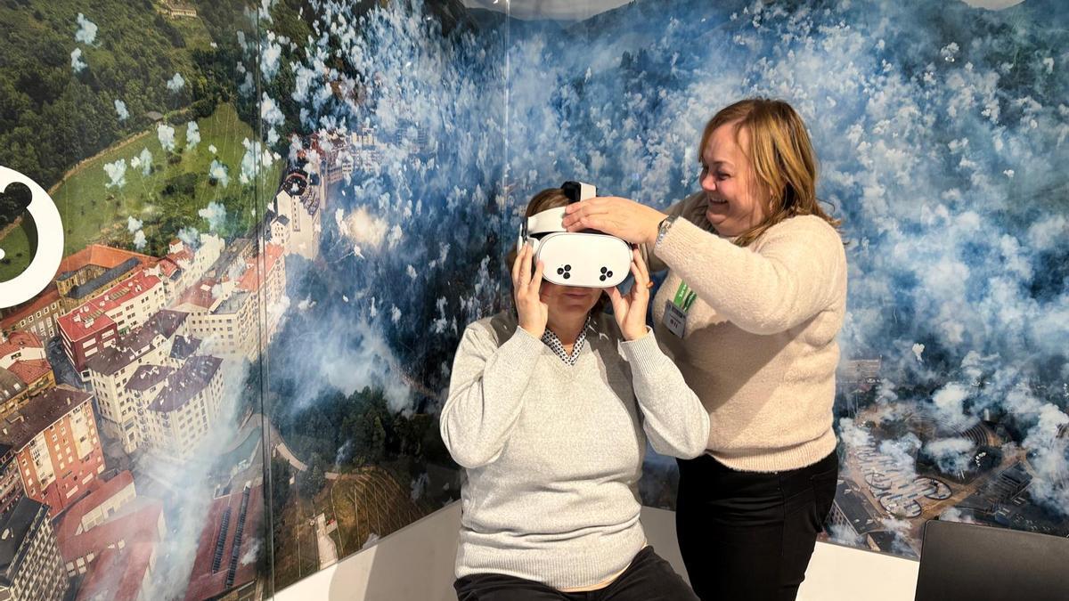 Carmen Rodríguez, responsable de la Oficina de Turismo, coloca las gafas de realidad virtual a Amelia Areces.