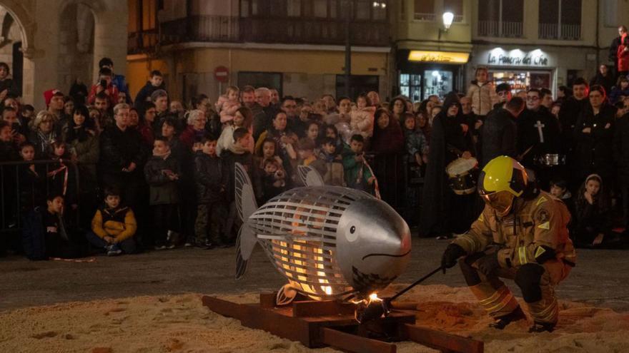 Un bombero ayuda a que arda la sardina.