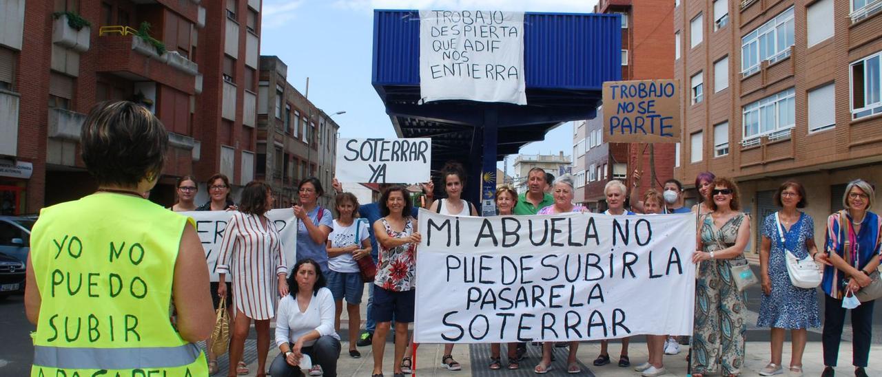 Integrantes de la Plataforma por el soterramiento del ferrocarril en San Andrés del Rabanedo, con pancartas reivindicativas, en Trobajo del Camino; detrás, la nueva pasarela peatonal. | Ramón Díaz