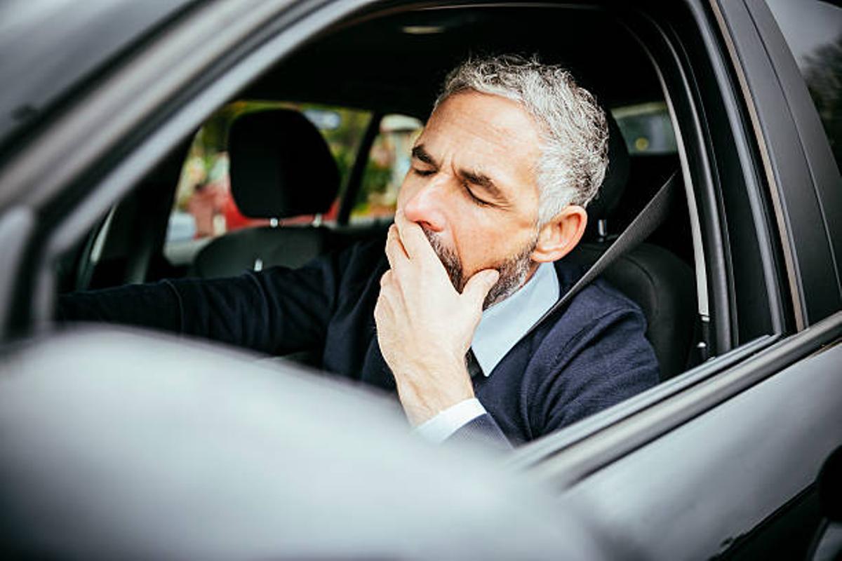 Un hombre bostezando mientras conduce