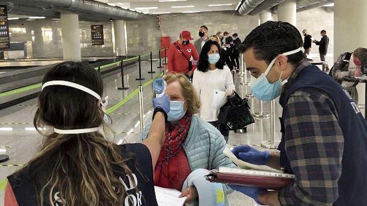 Personal de Sanidad Exterior toma la temperatura a pasajeros en Son Sant Joan.