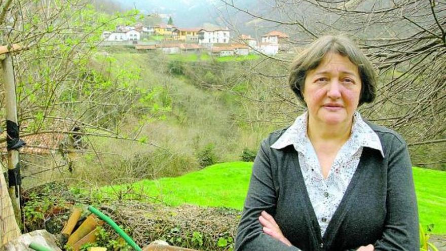 Raquel Varela Monasterio, en el exterior de su establecimiento, con uno de los barrios de San Juan de Beleño y la montaña al fondo. | ana paz paredes