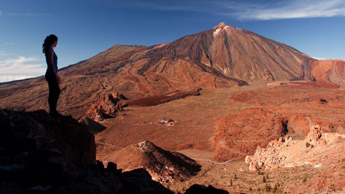 Una turista en la isla de Tenerife con el majestuoso pico del Teide al fondo. lp/dlp 17/02/2017 Brandcenter Turismo de Canarias / MOOD Naturaleza / Cuatro joyas de la naturaleza canaria y universal De la frondosidad de los bosques de Garajonay y la Caldera de Taburiente al sutil florecimiento de los lÃ­quenes que empiezan a colonizar la desnuda tierra volcÃ¡nica del Teide o Timanfaya: cuatro parques nacionales de relevancia planetaria muestran la enorme belleza y variedad ecolÃ³gica de Canarias ESPAÃ‘A EUROPA ISLAS CANARIAS ECONOMIA CEDIDA POR PROMOTUR