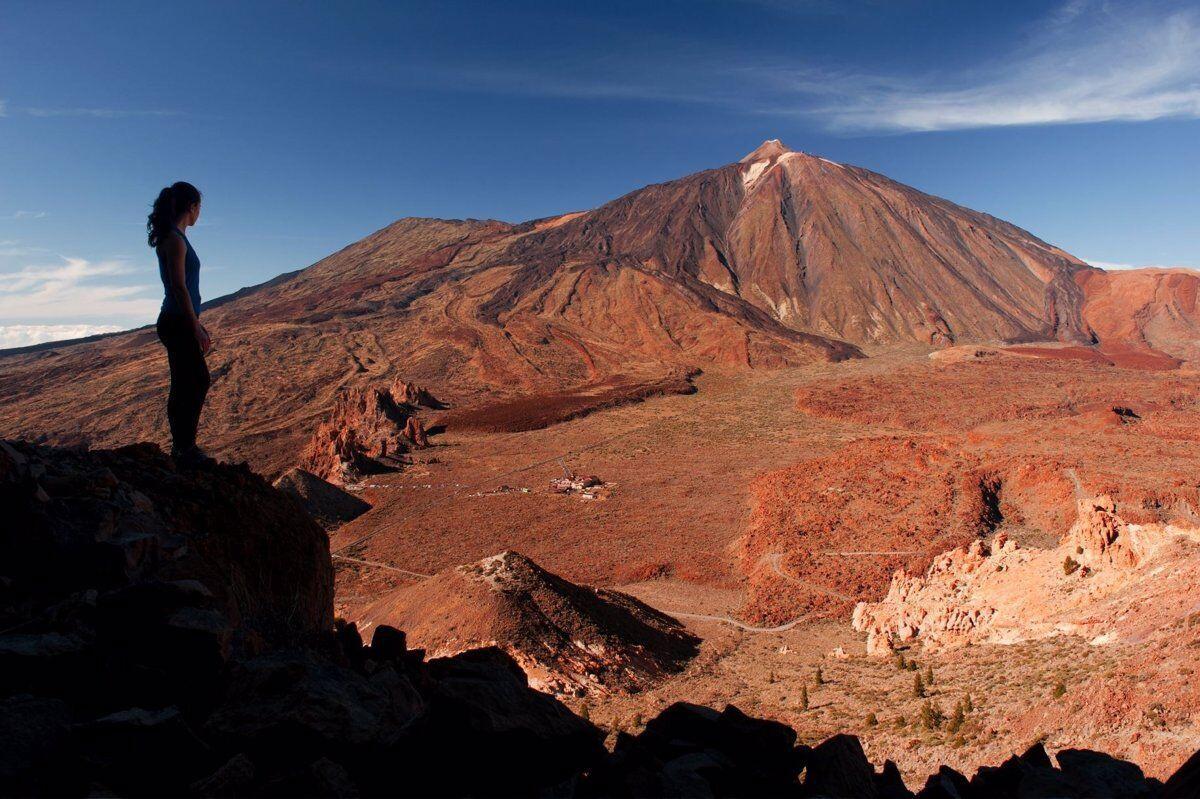 Una turista en la isla de Tenerife con el majestuoso pico del Teide al fondo. lp/dlp 17/02/2017 Brandcenter Turismo de Canarias / MOOD Naturaleza / Cuatro joyas de la naturaleza canaria y universal De la frondosidad de los bosques de Garajonay y la Caldera de Taburiente al sutil florecimiento de los lÃ­quenes que empiezan a colonizar la desnuda tierra volcÃ¡nica del Teide o Timanfaya: cuatro parques nacionales de relevancia planetaria muestran la enorme belleza y variedad ecolÃ³gica de Canarias ESPAÃ‘A EUROPA ISLAS CANARIAS ECONOMIA CEDIDA POR PROMOTUR