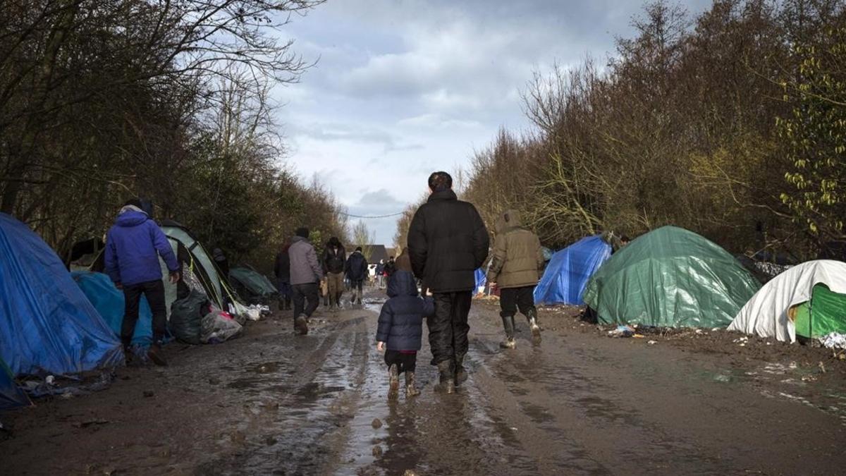 Un refugiado kurdo camina con su hijo por el campamento temporal montado en Grande-Synthe, cerca de Dunkerque, en el norte de Francia, el pasado 11 de enero.