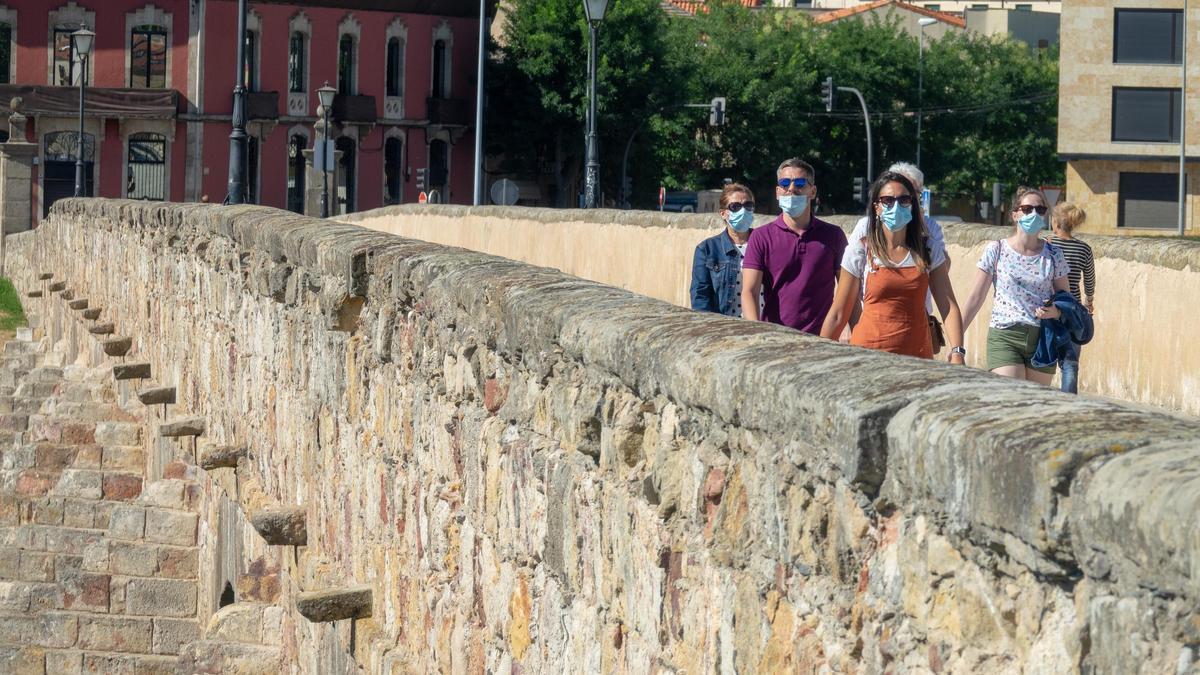 Turistas por pasean por el puente romano de la ciudad de Salamanca  durante la pandemia