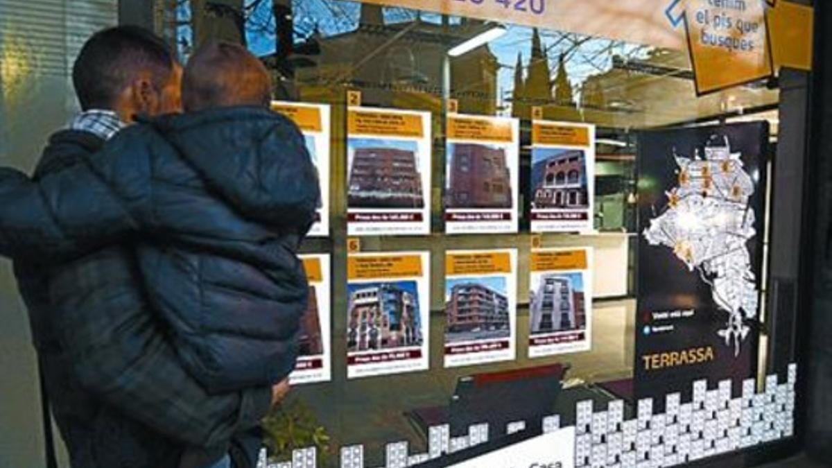 Una familia mira los anuncios de una inmobiliaria de Terrassa, ayer.