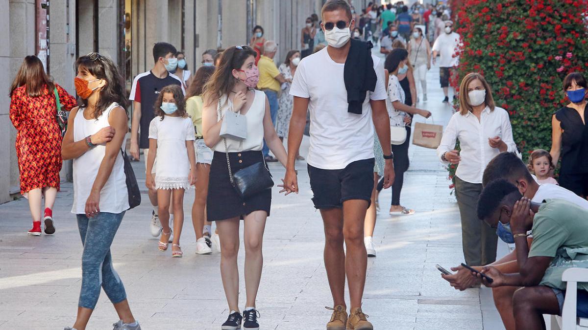 Gente con mascarilla pasea por la calle Príncipe en Vigo.